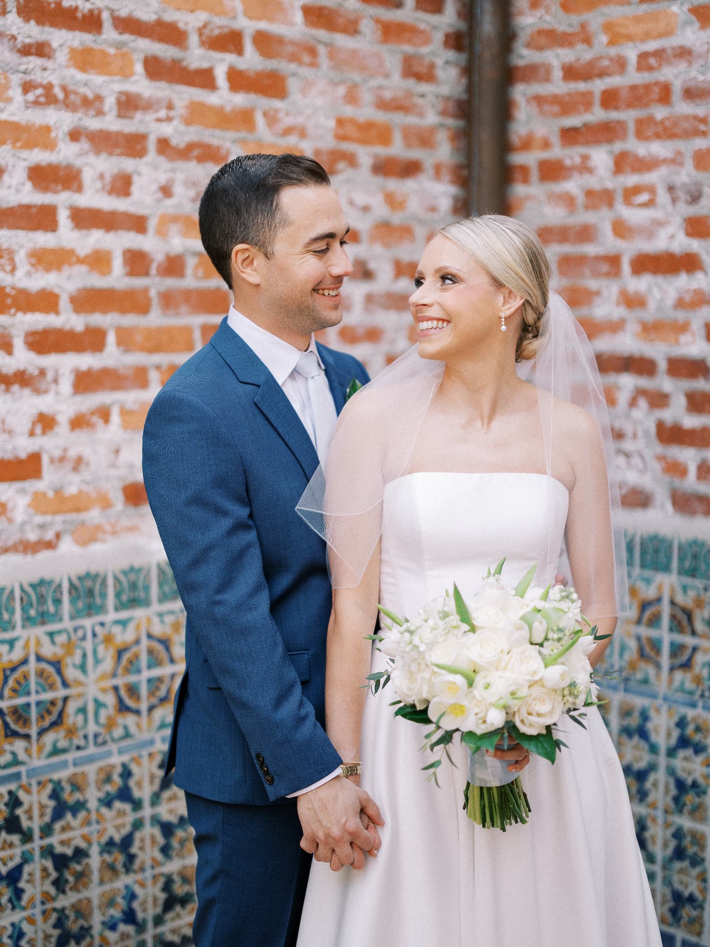 Bride and groom in front of a brick wall