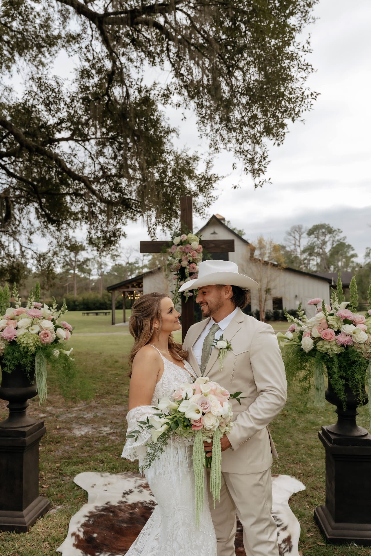 Bride and groom beneath a floral cross