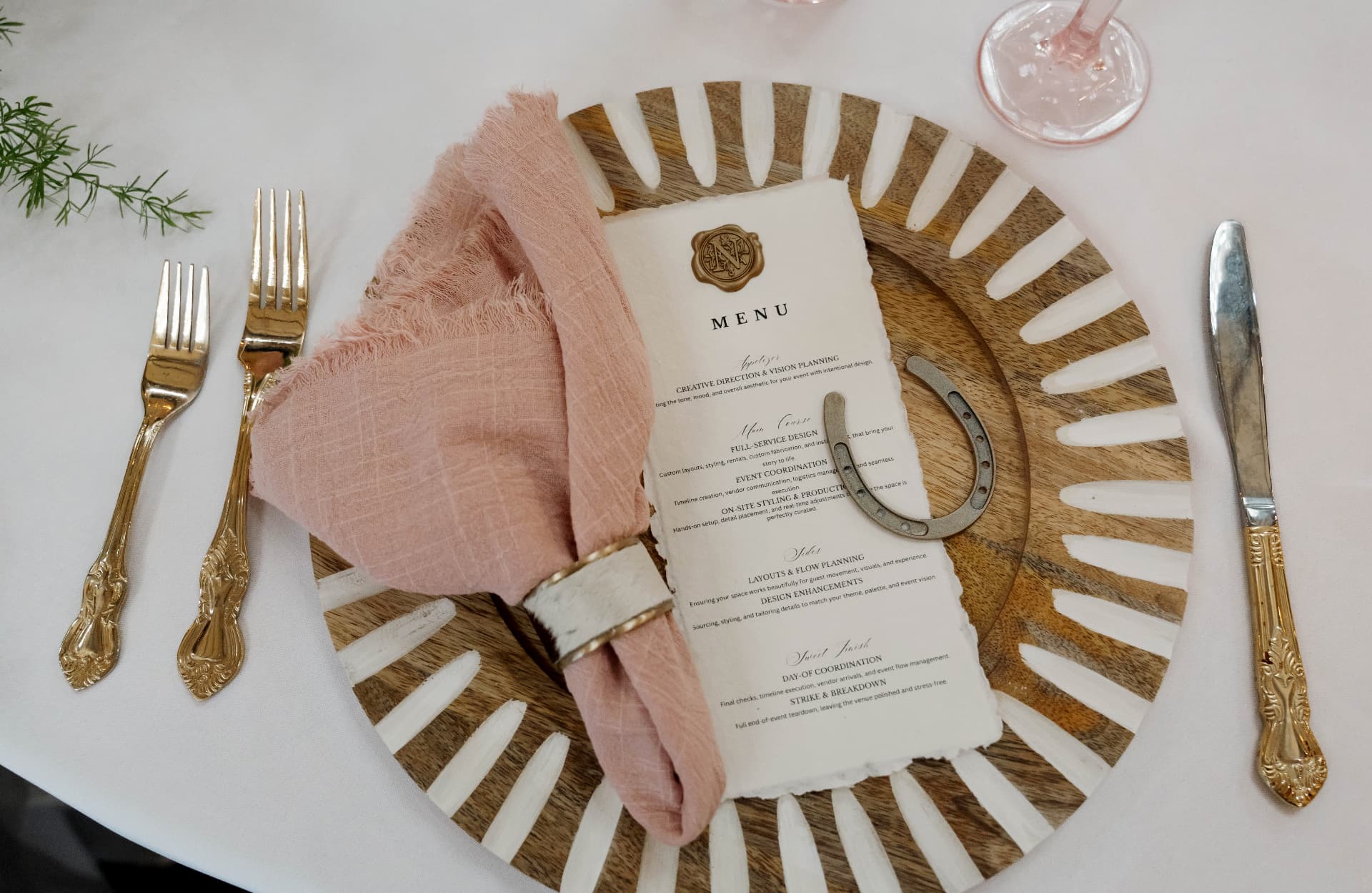 Place setting with gold flatware and a pink napkin