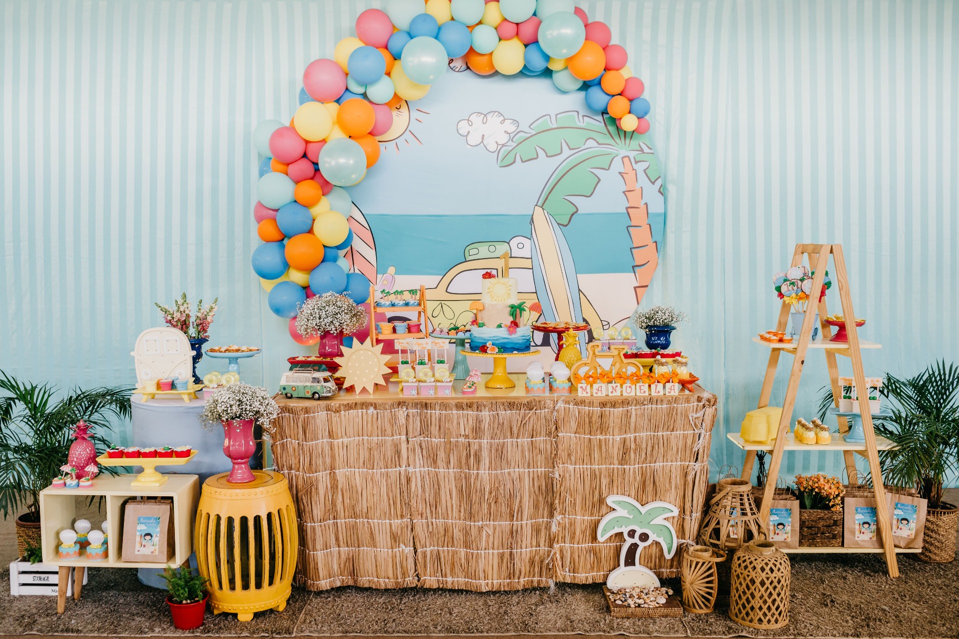 First birthday party with a balloon arch, striped backdrop and a cake with a number one topper